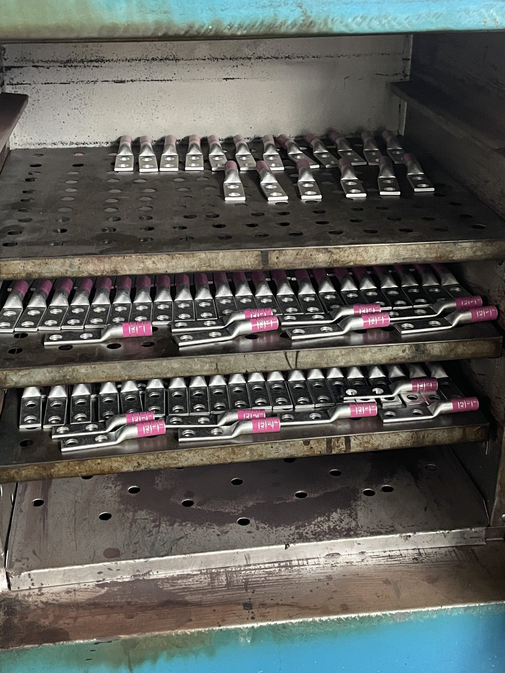 The manufacturing and color-printing process of Xluig compression lugs, highlighting industry-standard coding for error-free wire identification.